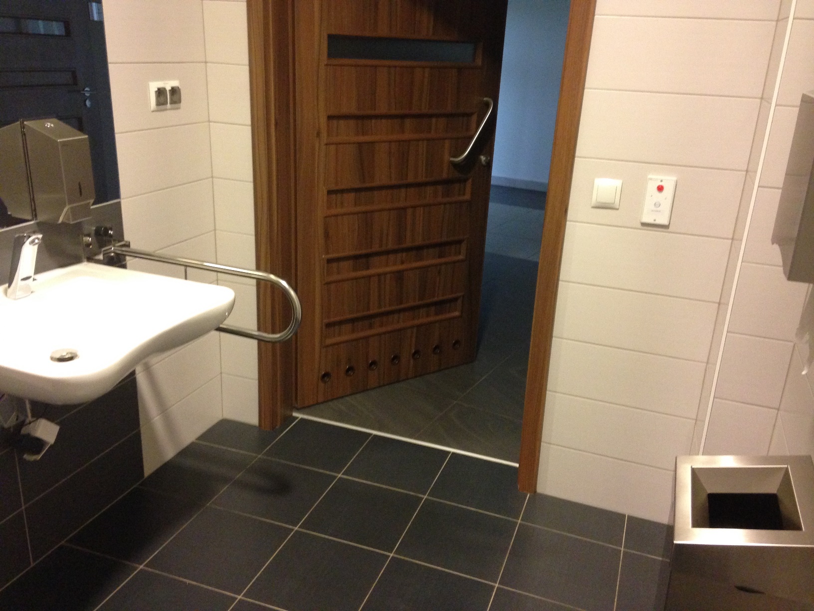 Wejście do toalety, przestrzeń pomiędzy umywalką o metalowym dozownikiem i koszem - 118 cm